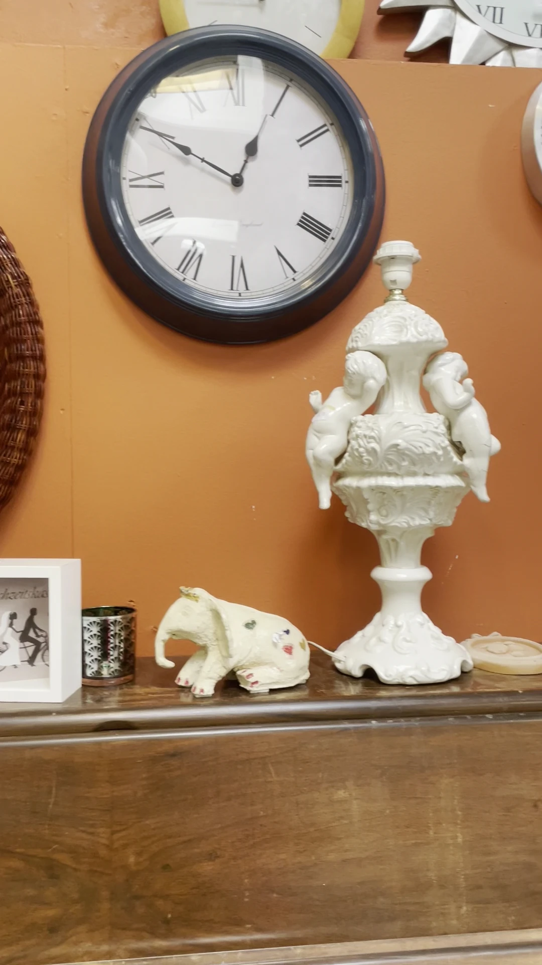Witte decoratieve porseleinen urn met handvaten en vogelornament naast een witte porseleine olifantbeeldje