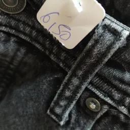 Close-up van een donkergrijs gebreide trui met knoop, op een prijskaartje