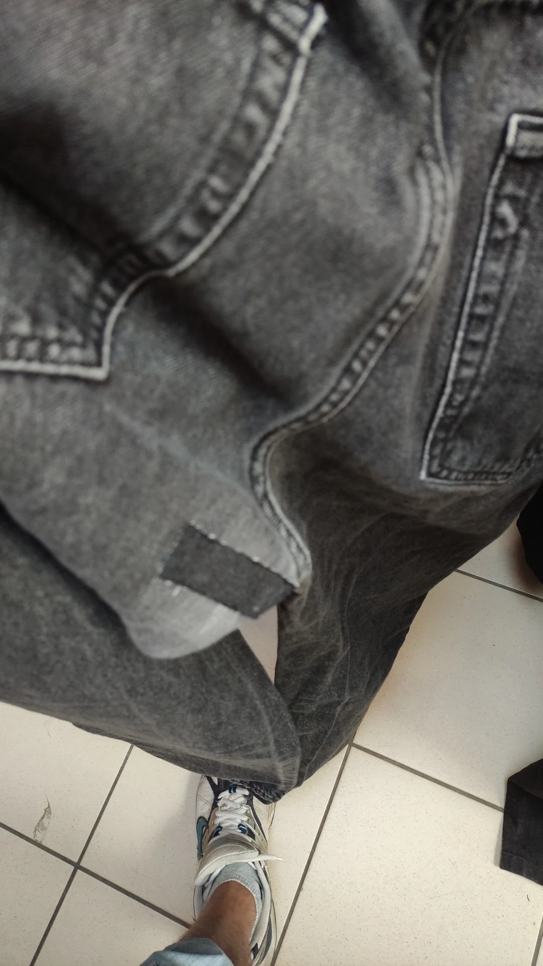 Close-up van een grijze jeans met scheuren op het bovenbeen