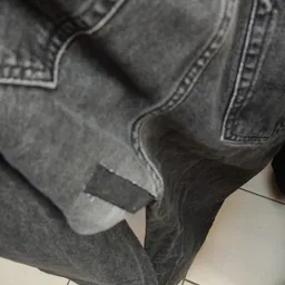 Close-up van een grijze jeans met scheuren op het bovenbeen
