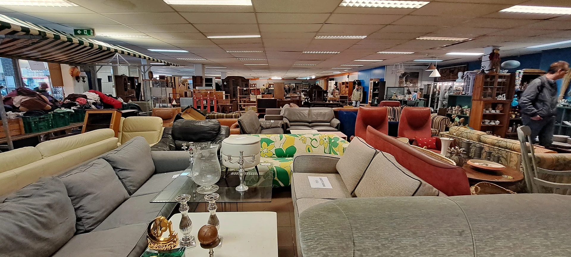 Meubels in de kringloopwinkel: banken, fauteuils en stoelen in verschillende kleuren en stijlen uitgestald