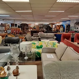 Meubels in de kringloopwinkel: banken, fauteuils en stoelen in verschillende kleuren en stijlen uitgestald