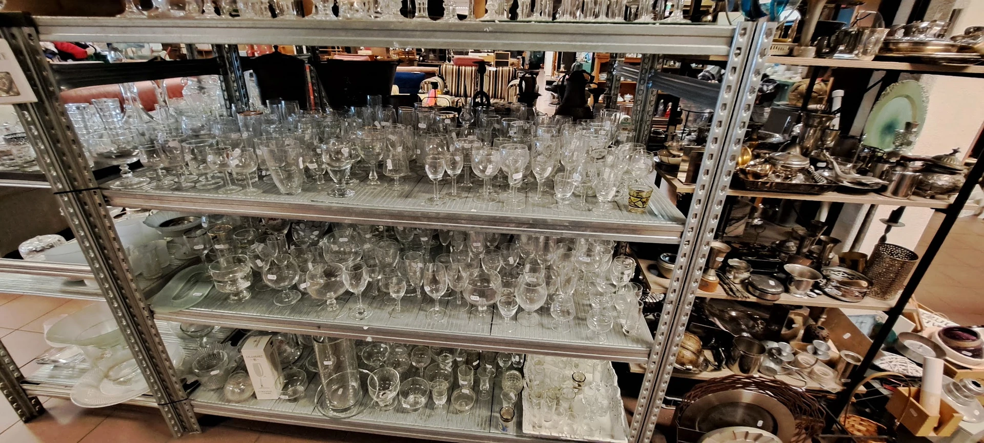 Glazen schappen vol met diverse glazen en drinkglazen in verschillende vormen en maten