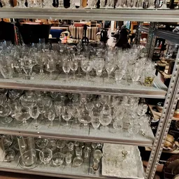 Glazen schappen vol met diverse glazen en drinkglazen in verschillende vormen en maten