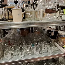 Glazen en drinkglazen uitgestald op planken in de kringloopwinkel