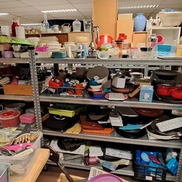 Metalen stellingen met diverse huishoudelijke artikelen, servies, pannen en andere gebruiksartikelen