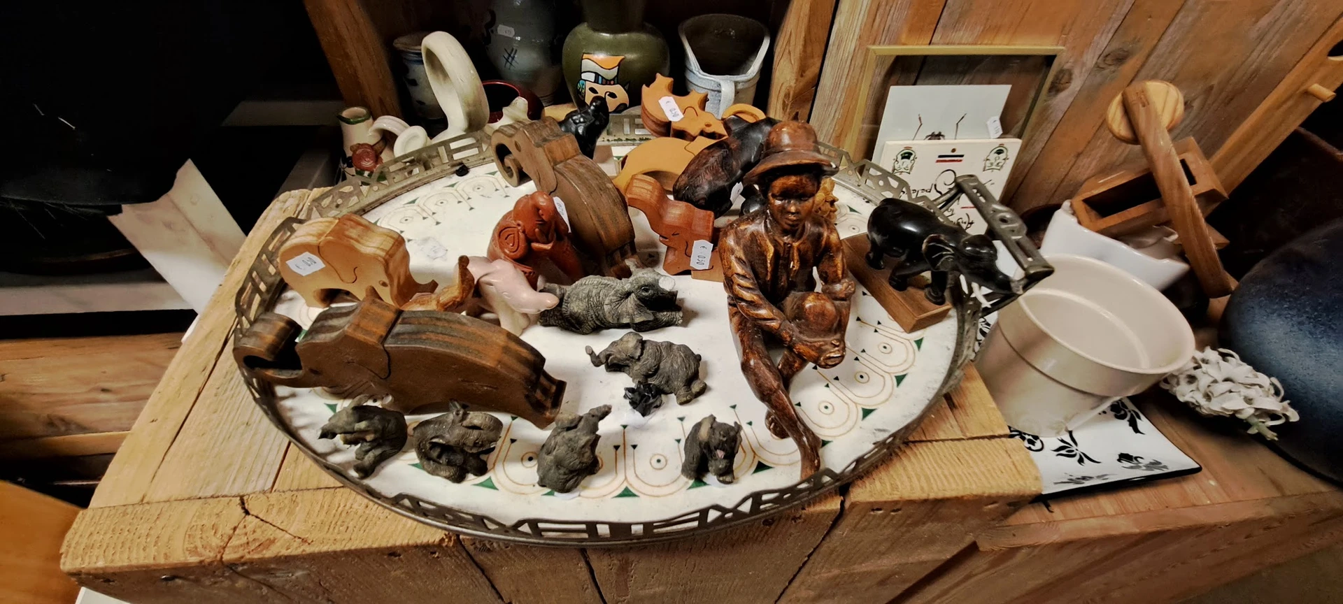 Verzameling houten beeldjes, dierenfiguren en decoratieve voorwerpen uitgestald op een rond wit bord