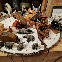 Verzameling houten beeldjes, dierenfiguren en decoratieve voorwerpen uitgestald op een rond wit bord