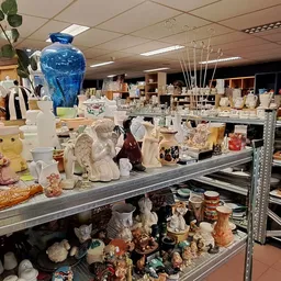 Stellingen en toonbank volgestapeld met diverse huishoudelijke artikelen, vazen, beelden en decoratieve voorwerpen in een kri