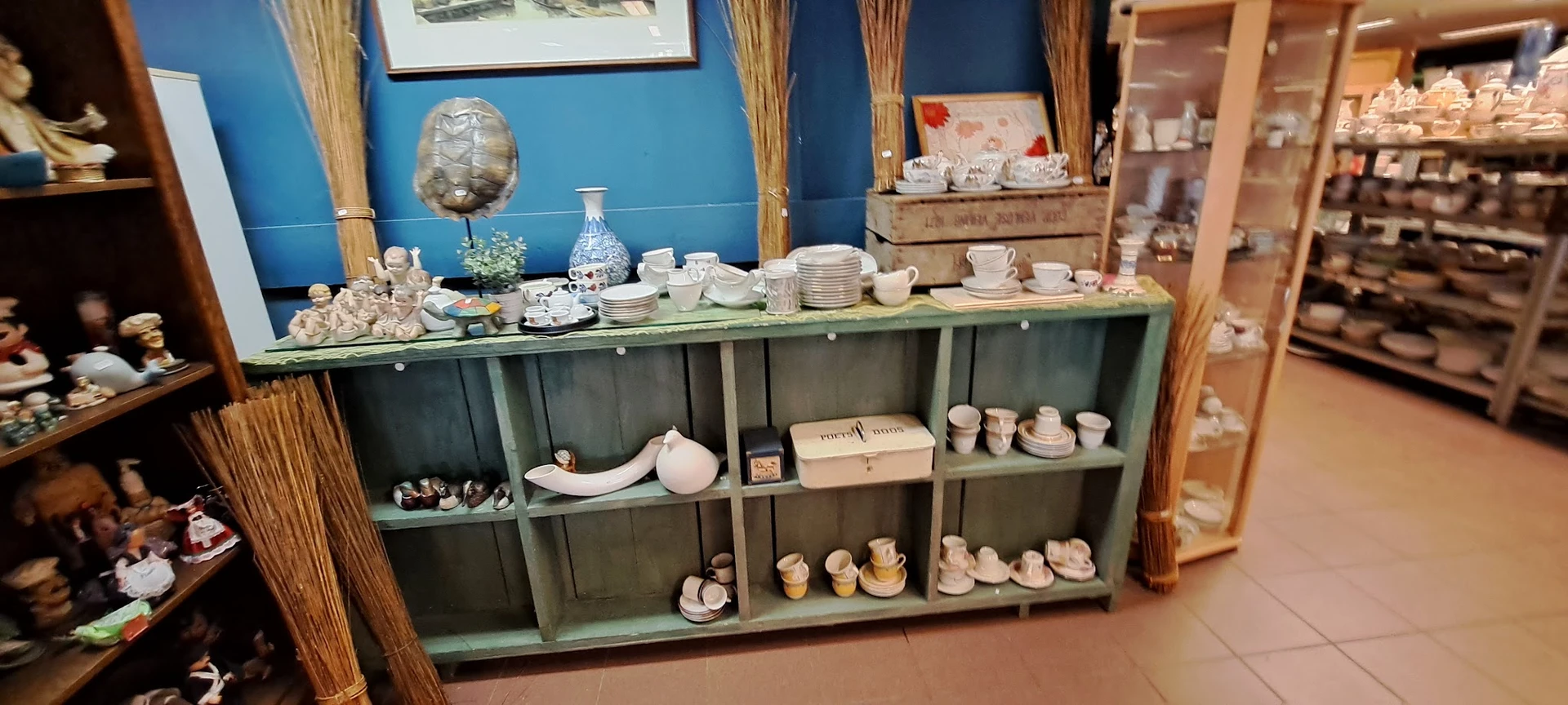 Groene stellingkast met servies, borden, kopjes en decoratieve voorwerpen netjes uitgestald