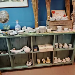 Groene stellingkast met servies, borden, kopjes en decoratieve voorwerpen netjes uitgestald