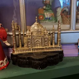 Gouden miniatuurnachteming van de Taj Mahal met zwart voetje tussen andere decoratieve artikelen in de winkel