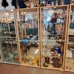Vitrinekasten met diverse glazen, servies, decoratieve items en huishoudartikelen in een kringloopwinkel