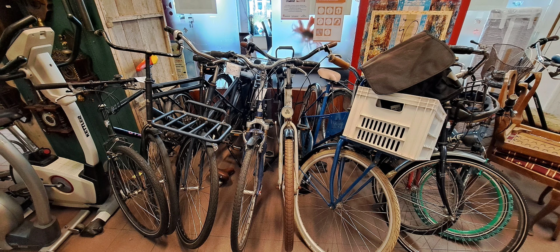 Verzameling tweedehands fietsen en fietsonderdelen uitgestald in de winkel