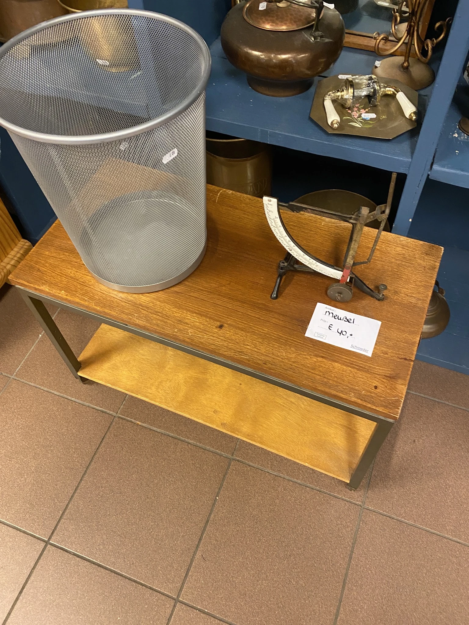 Houten tafel met zwarte metalen poten met daarop een grijze wasmand, glazen vazen en een prijskaartje van 6,50 euro
