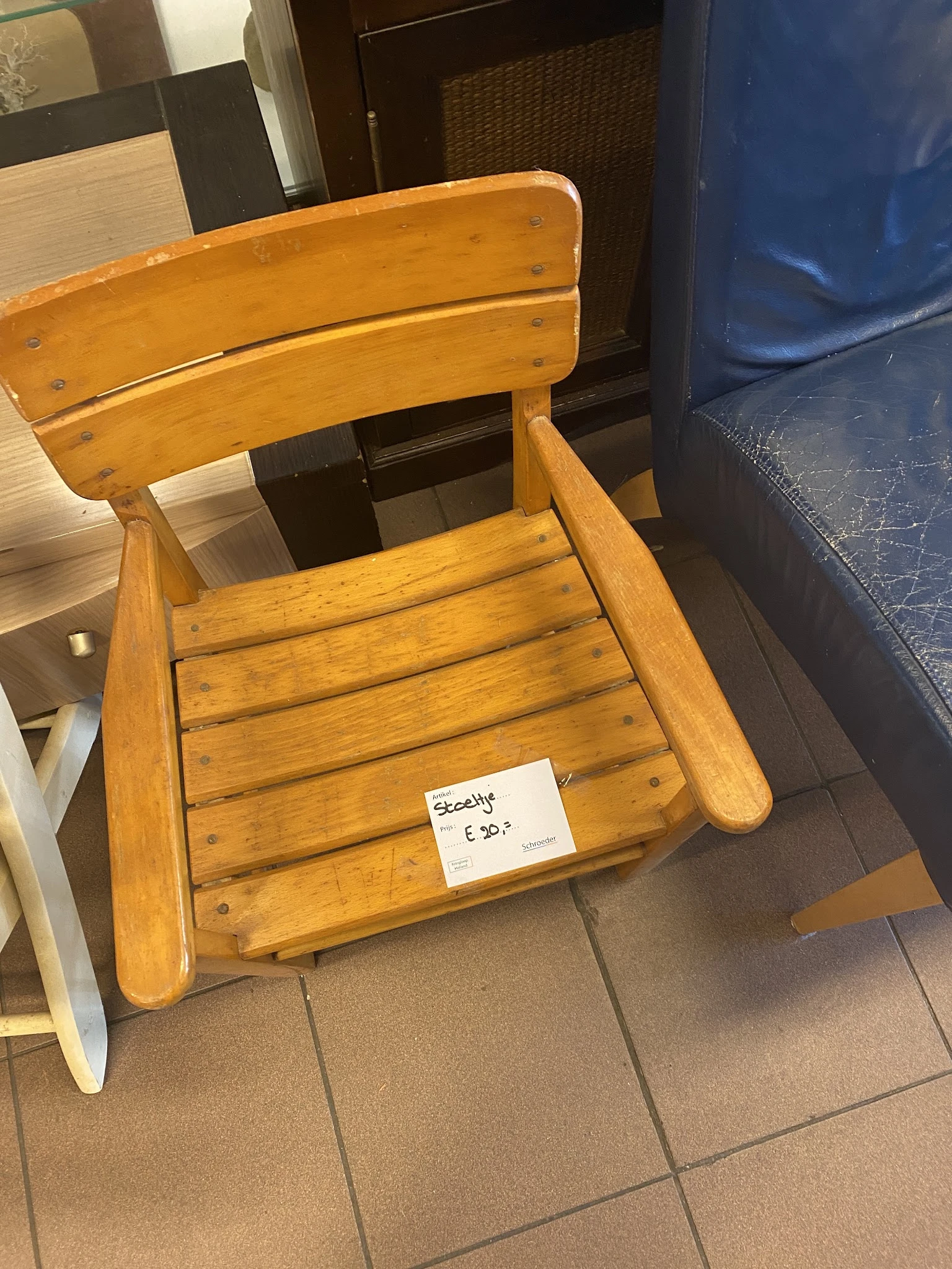 Houten stoel met armleuningen en horizontale latten, voorzien van een prijskaartje van €50
