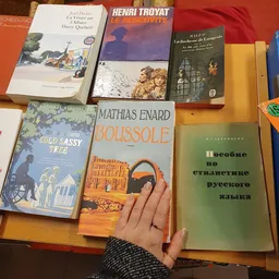 Tweedehands boeken uitgestald op tafel, waaronder werken van Mathias Enard en Russische taalhandboeken