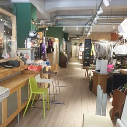 Winkelvloer van kringloopwinkel met rekken met kleding, houten toonbank met groene stoel, groene muur op achtergrond