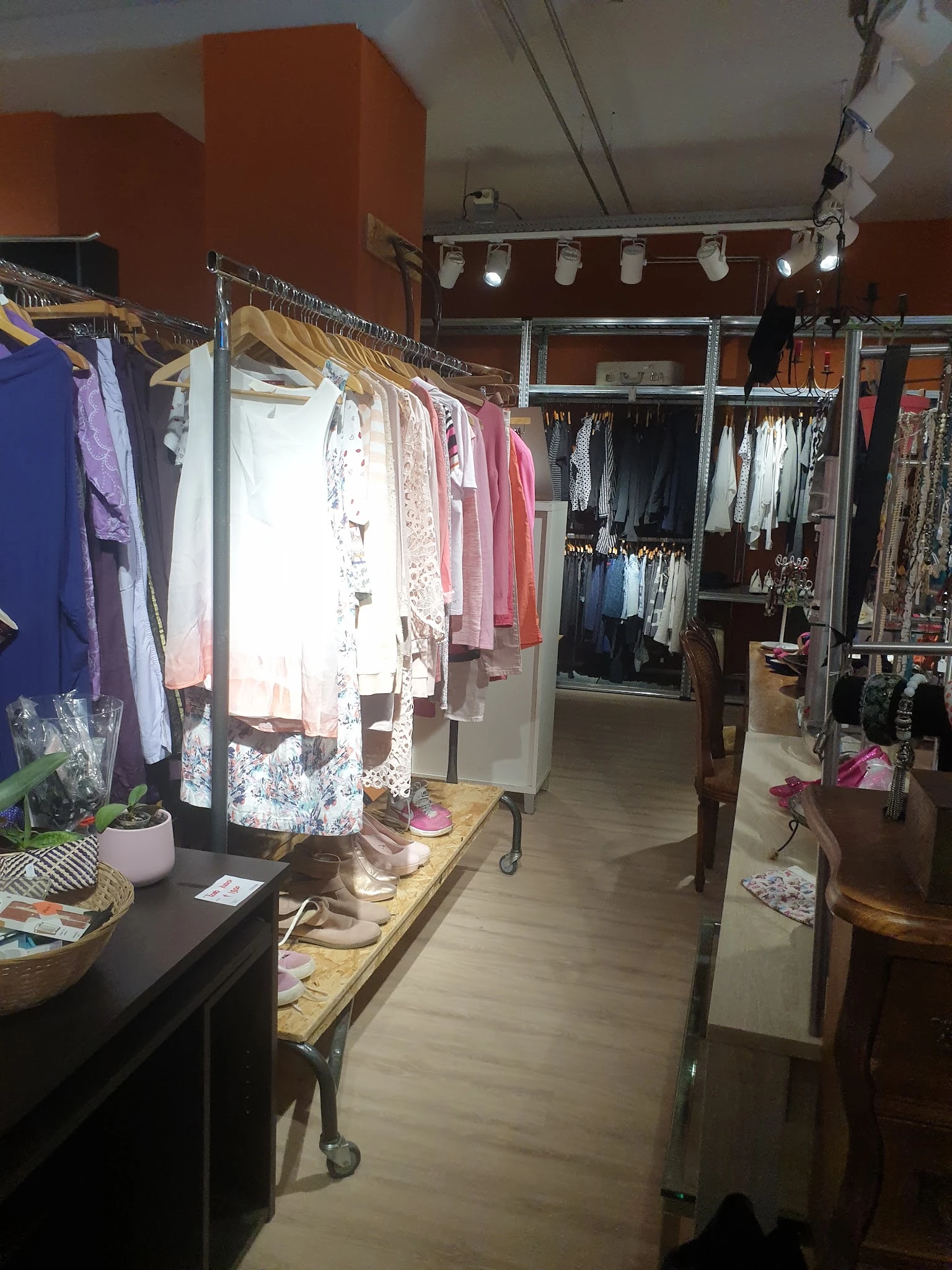 Winkelvloer met kledingrekken vol tweedehands kleding in verschillende kleuren en stijlen