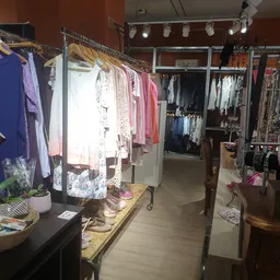 Winkelvloer met kledingrekken vol tweedehands kleding in verschillende kleuren en stijlen