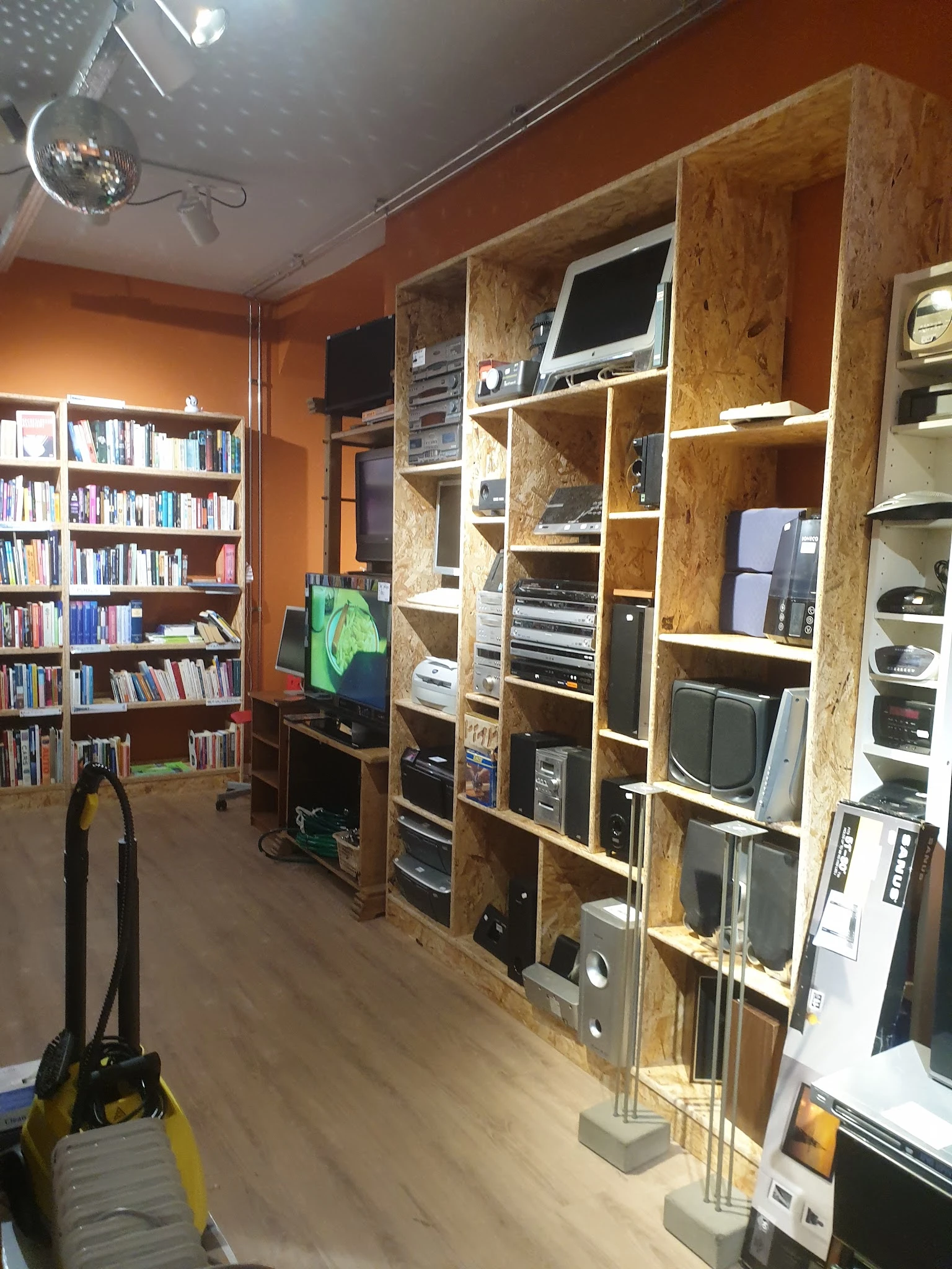 Winkelvloer met boekenkasten links, houten stellingkasten met elektronische apparatuur en computers in het midden en rechts