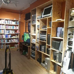 Winkelvloer met boekenkasten links, houten stellingkasten met elektronische apparatuur en computers in het midden en rechts
