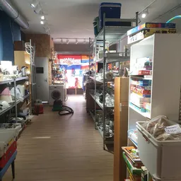 Winkelinterieur van kringloopwinkel met stellingen, schappen en diverse tweedehands artikelen langs de wanden