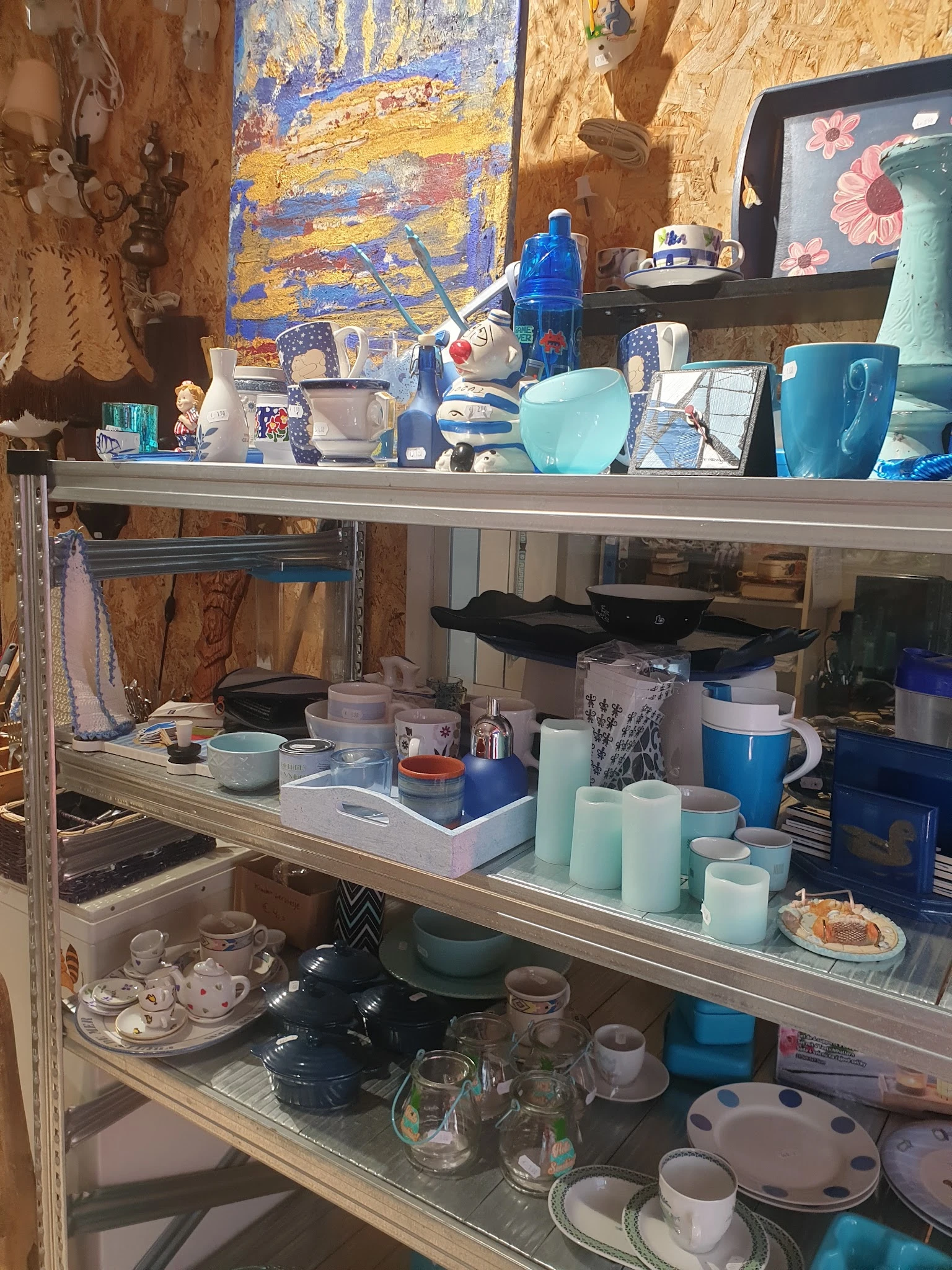 Stellingen met huishoudartikelen zoals servies, bekers, pannen en keukenspullen