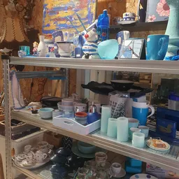 Stellingen met huishoudartikelen zoals servies, bekers, pannen en keukenspullen