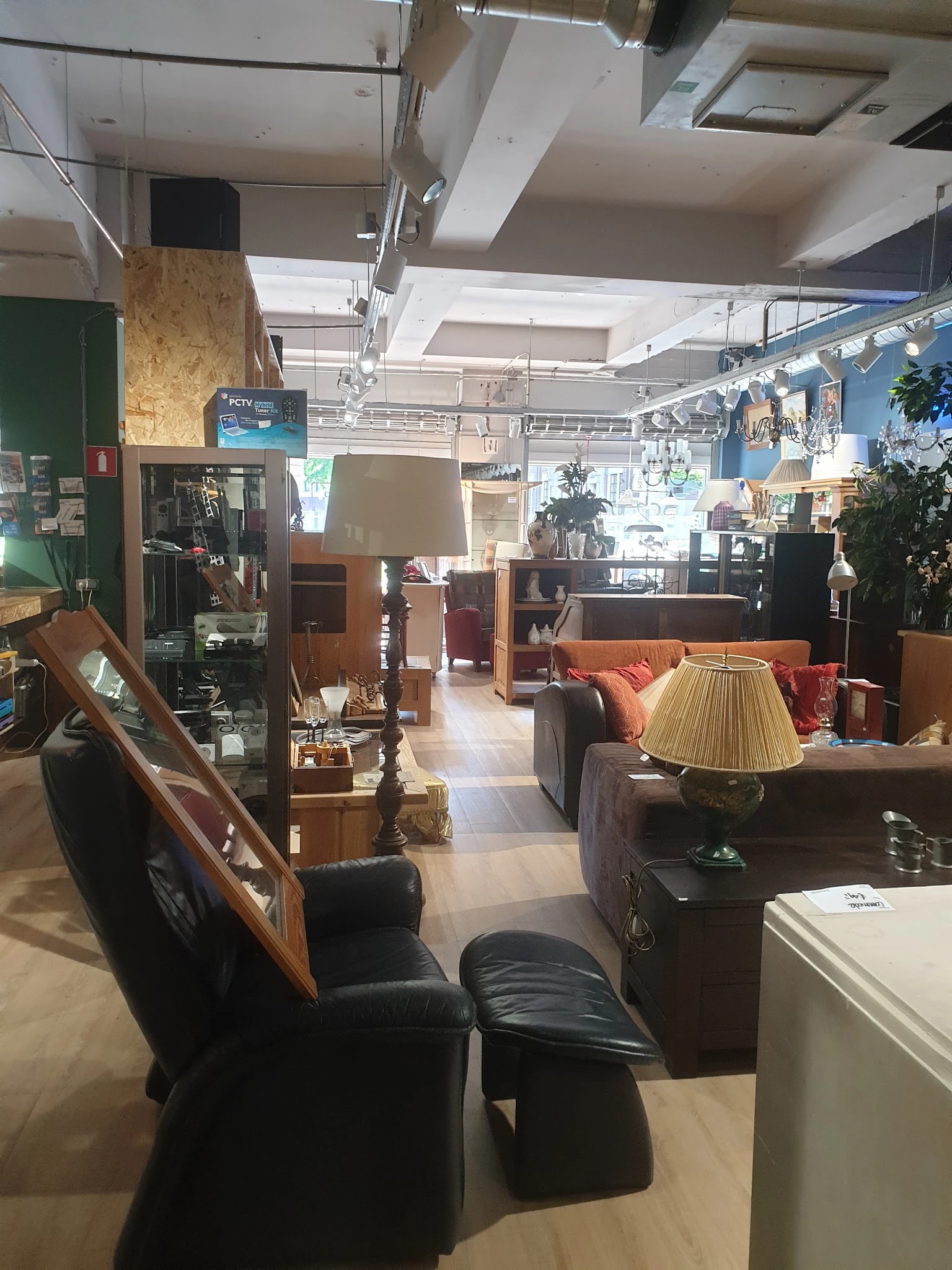 Winkelvloer van kringloopwinkel met meubels, lampen, planten en diverse huishoudelijke artikelen