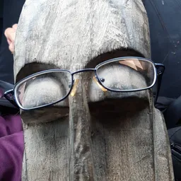 Bril met metalen montuur op een houten paal