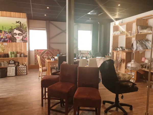 Winkelbinnenruimte met bruine stoelen, houten stellingen, ramen en houten vloer
