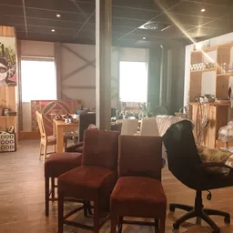 Winkelbinnenruimte met bruine stoelen, houten stellingen, ramen en houten vloer