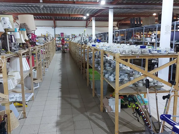 Winkelvloer met houten stellingen vol serviesgoed en huishoudelijke artikelen in een kringloopwinkel