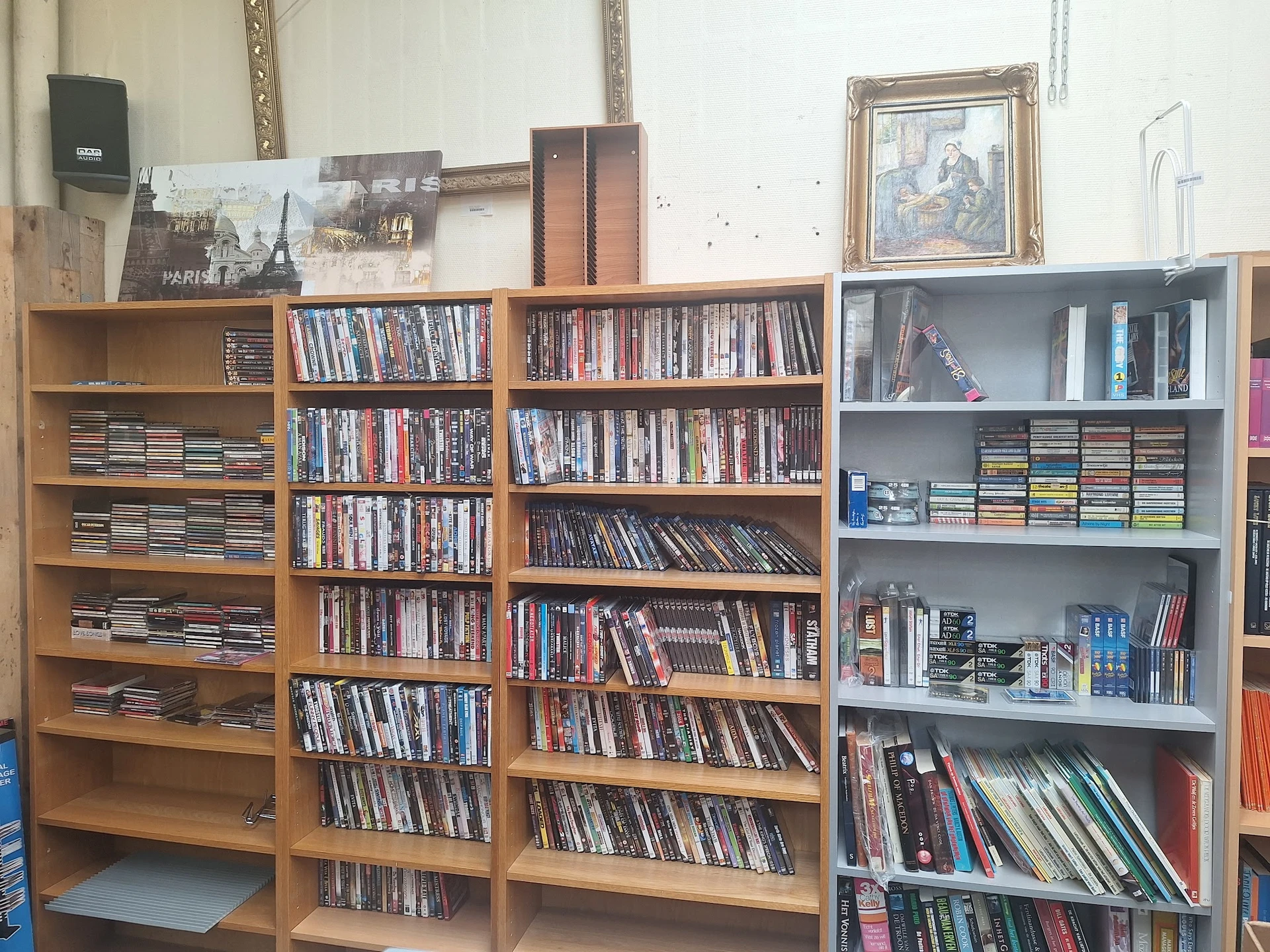 Houten en grijze stellingen vol met dvd's, blu-rays en cd's in de kringloopwinkel