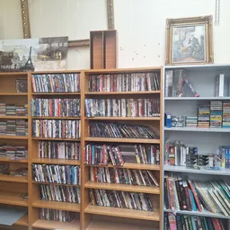 Houten en grijze stellingen vol met dvd's, blu-rays en cd's in de kringloopwinkel