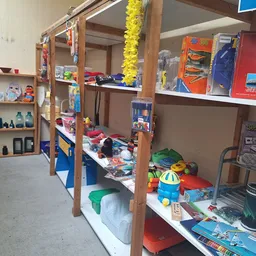 Winkelinterieur met houten stellingen volgestapeld met speelgoed, boeken en diverse artikelen