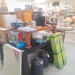 Winkelvloer met diverse huishoudelijke items, meubels en dozen op en rond een tafel