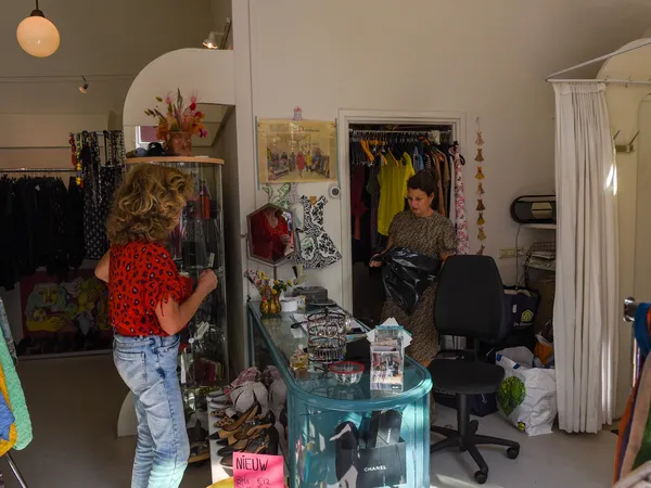Winkelvloer met kledingrekken, spiegels, een turquoise tafel en winkelmeubels in een tweedehandswinkel