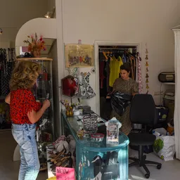 Winkelvloer met kledingrekken, spiegels, een turquoise tafel en winkelmeubels in een tweedehandswinkel