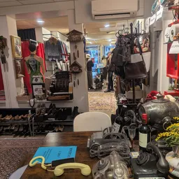 Winkelvloer van tweedehands winkel met kledingrekken, tassen, accessoires en decoratieve objecten