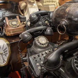 Verzameling vintage telefoons en klokken uitgestald op houten oppervlakken