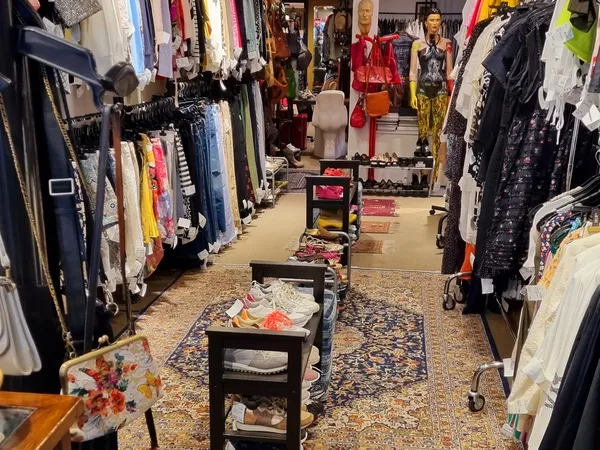 Winkelvloer met kledingrekken aan beide zijden en display-tafels in het midden, gevuld met tweedehands kleding en accessoires