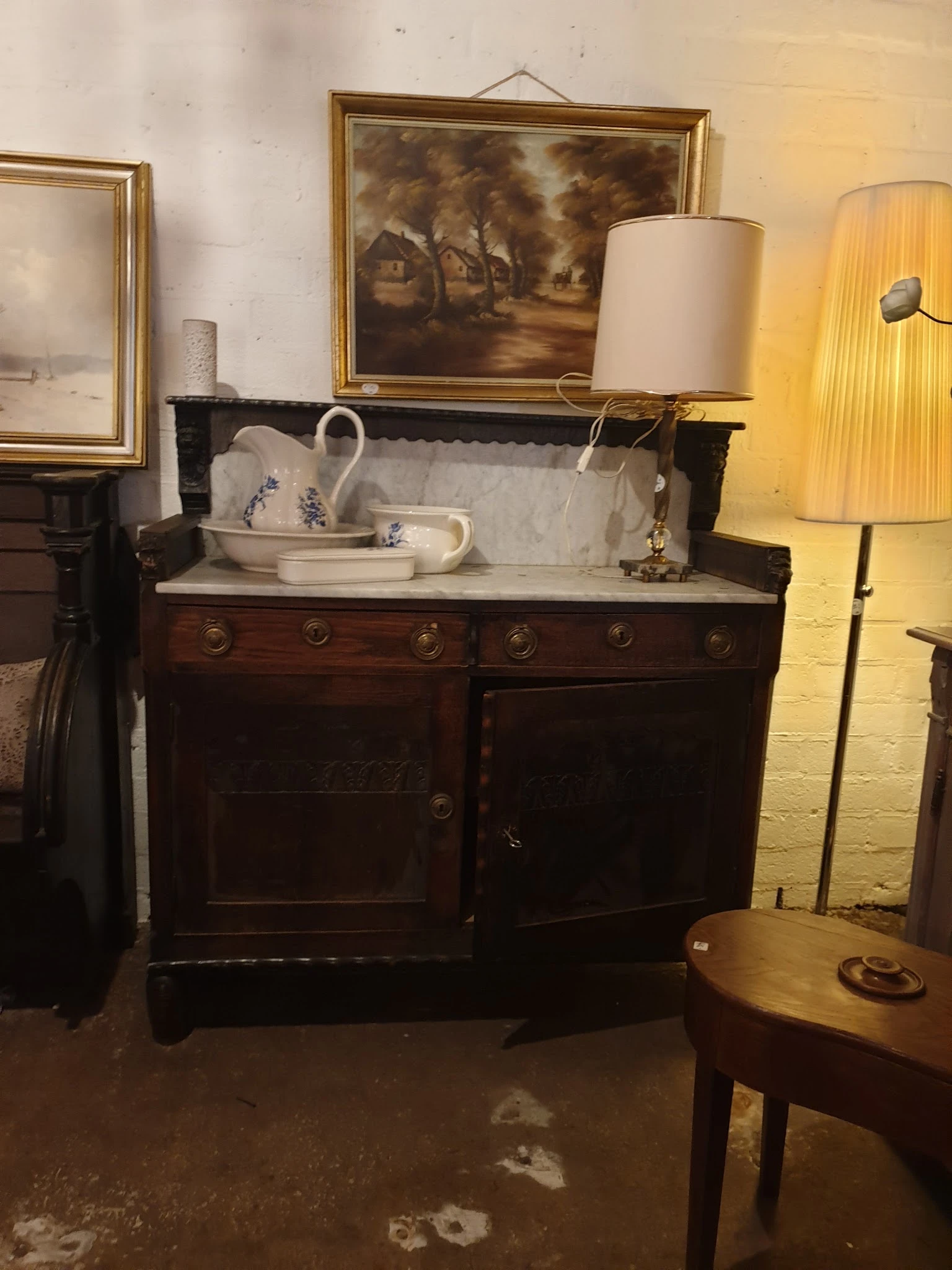 Antieke donkerhouten commode met marmeren blad en wit porselein servies erop