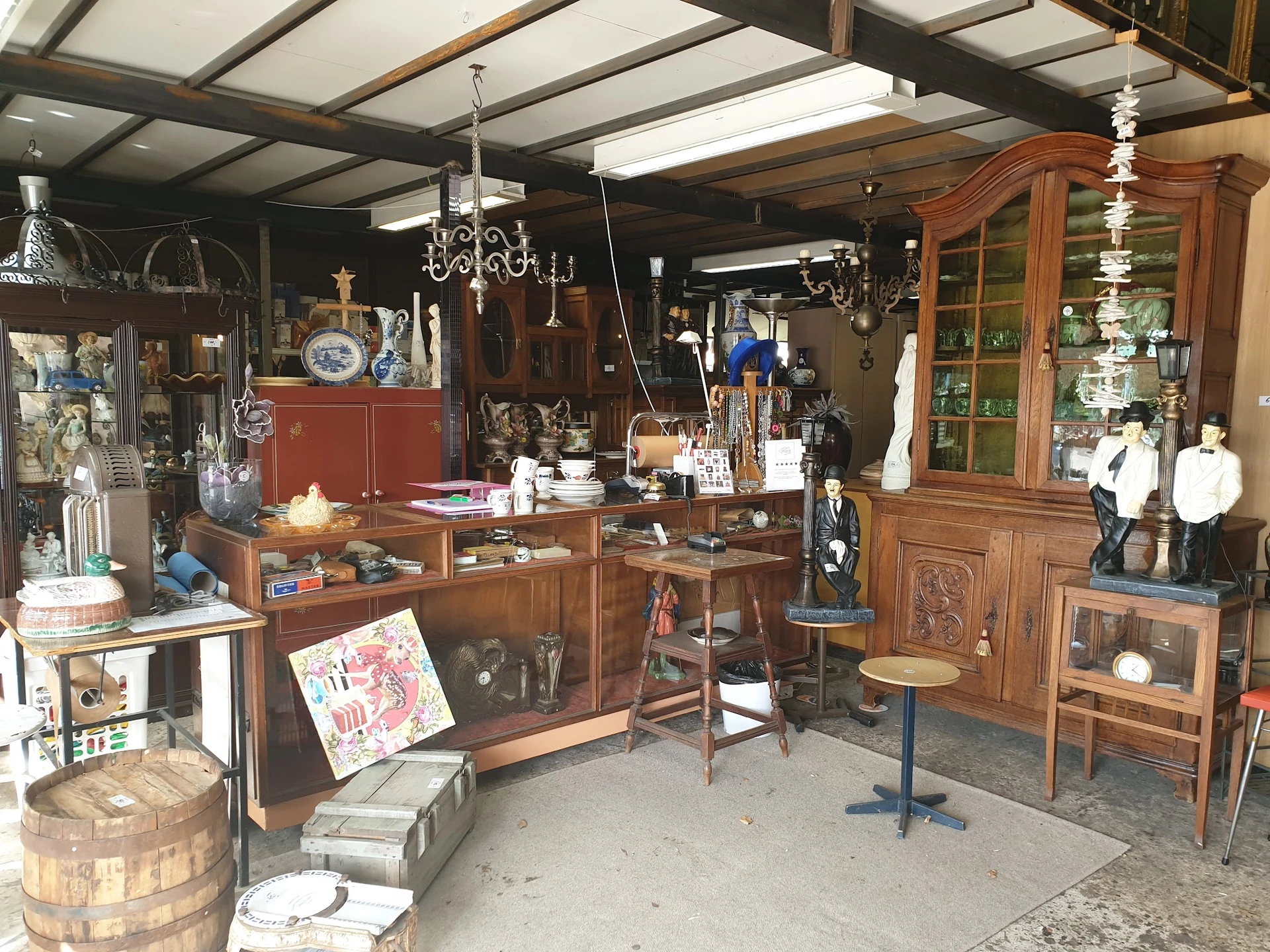Overzicht van winkelvloer met houten meubels, vitrines, kroonluchters en diverse antiquiteiten en decoratieartikelen