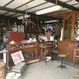 Overzicht van winkelvloer met houten meubels, vitrines, kroonluchters en diverse antiquiteiten en decoratieartikelen