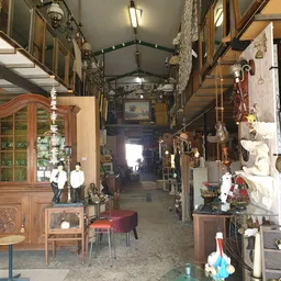 Interieur van kringloopwinkel met houten meubels, decoratieve objecten en diverse spullen langs beide zijden van een gangpad