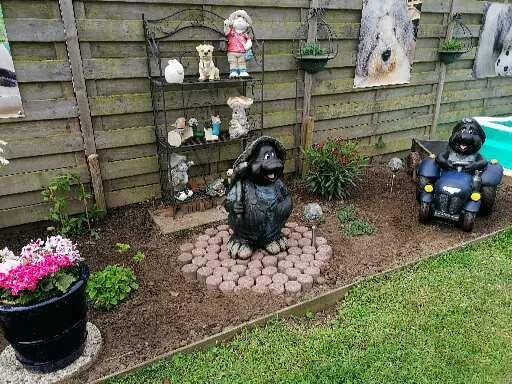 Tuinhoek met decoratieve beelden, bloemen en kunstig aangelegde stenen