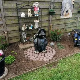 Tuinhoek met decoratieve beelden, bloemen en kunstig aangelegde stenen