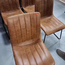 Close-up van twee bruine lederen stoelen met stiksels en metalen poten